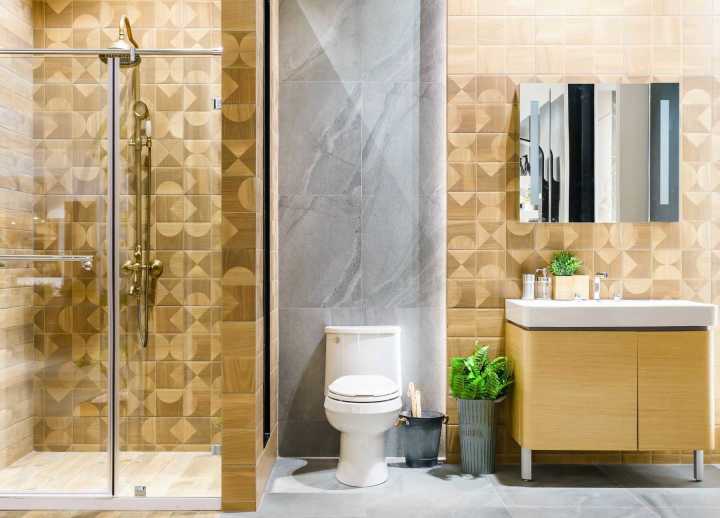 Không gian nhà vệ sinh hiện đại kết hợp với phòng tắm kính cùng  gạch ốp tường đá marble vân hình học nâu vàng đẹp mắt