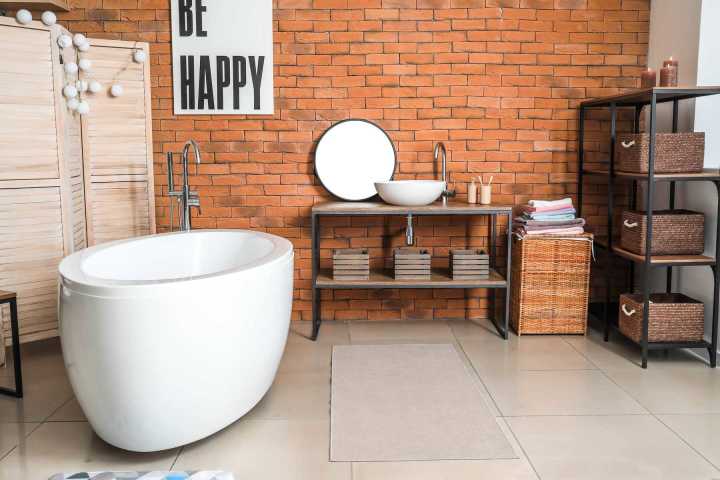 Nhà vệ sinh thiết kế phong cách mộc mạc với tường gạch và các kệ treo